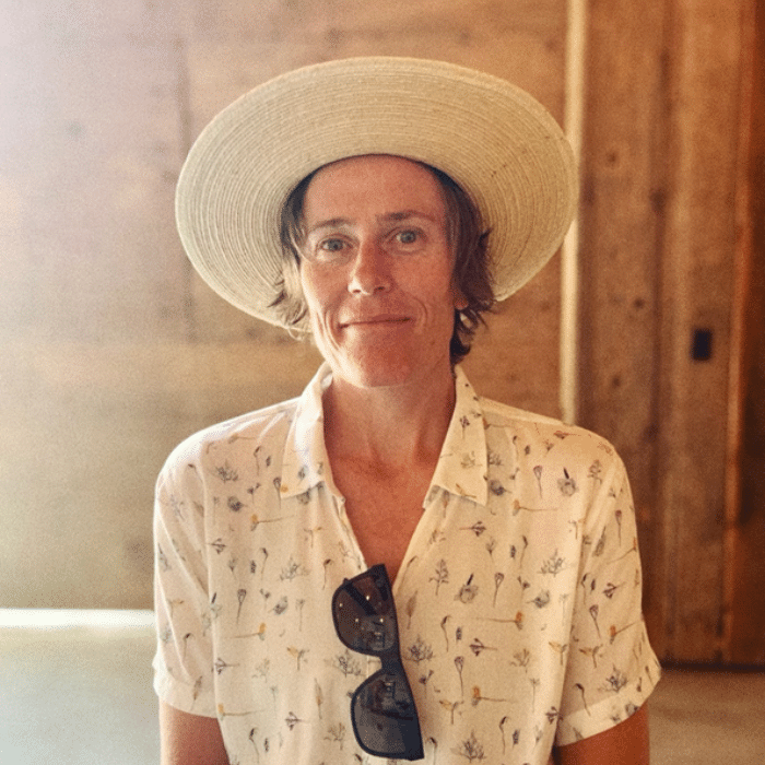 Andrea Wing wearing a wide-brimmed hat, patterned collared t-shirt and sunglasses hanging from neckline.