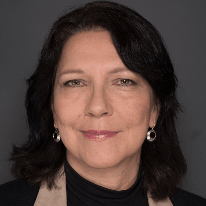 Barbara Todd Hager with dark shoulder-length hair, high-neck black shirt and silver earrings.