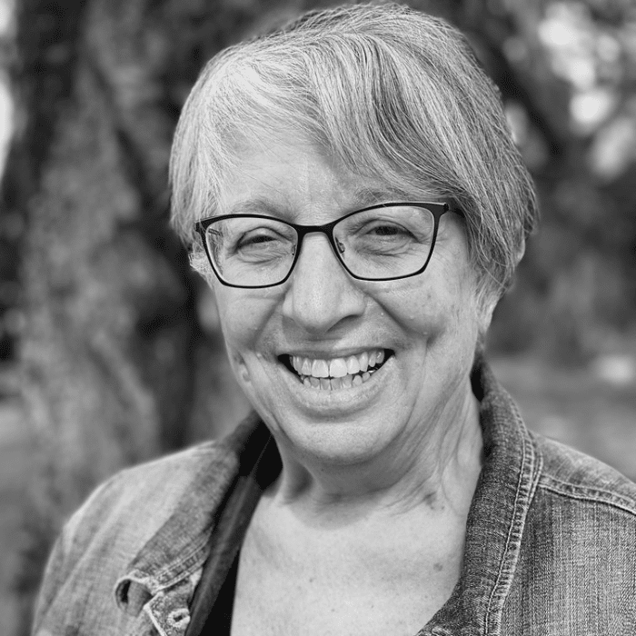 Black and white headshot of Cari Green wearing glasses and a jean jacket.
