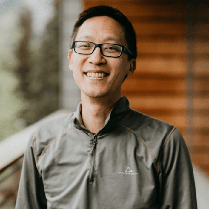 Chris Hsiung with short dark hair, glasses and a green zip-up shirt.