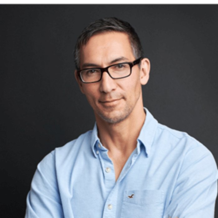 Corey Lee with short, dark hair, glasses and a light blue button-up shirt.