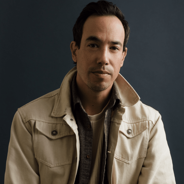 Danny Berish with short, dark hair wearing a beige jacket with a dark collared shirt underneath.