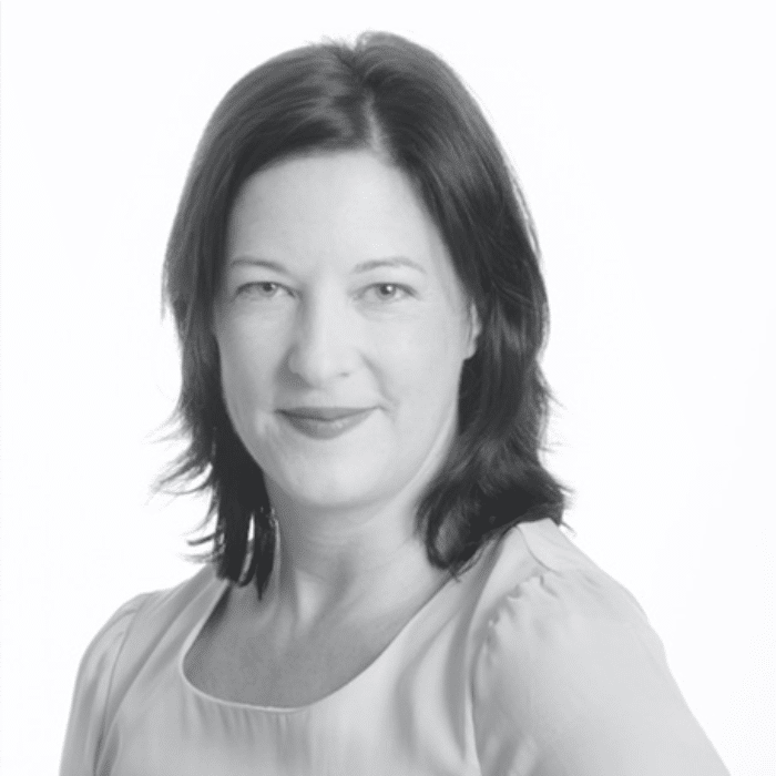 Black and white headshot of Leah Mallen with dark shoulder length hair wearing a light-coloured shirt.