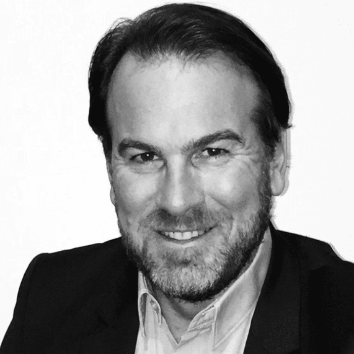 Black and white headshot of Lionel Vialaneix with short dark hair, facial hair wearing a black blazer with a light-coloured collared shirt underneath.