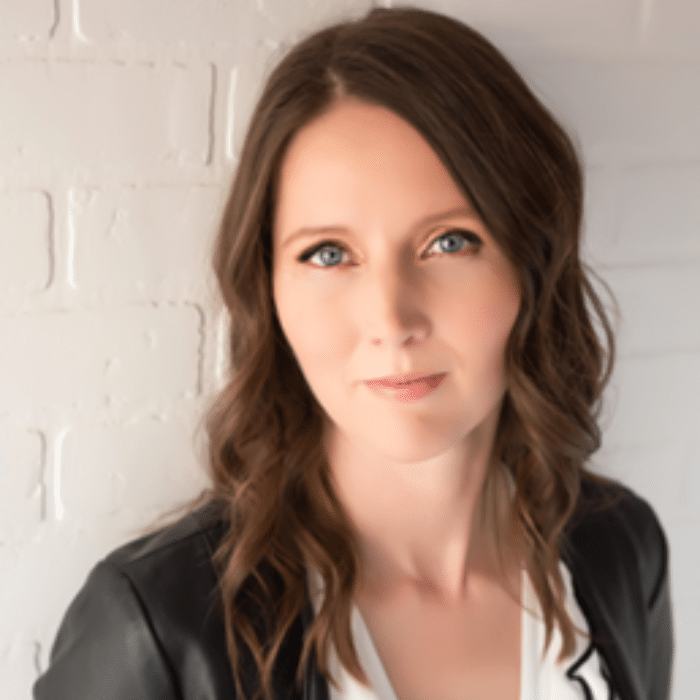 Rebecca Campbell with long brown hair, wearing a black leather jacket and white shirt.