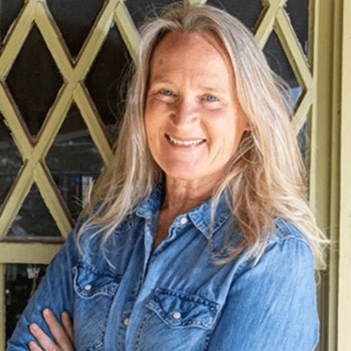 Sandi Somers with long white blonde hair wearing a denim button-up shirt.