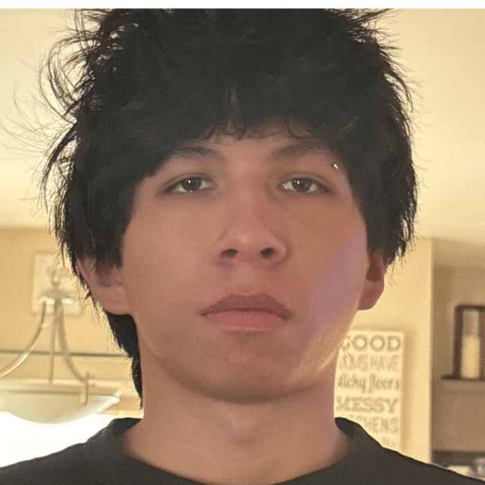 Person with short dark hair looking straight at the camera indoors.