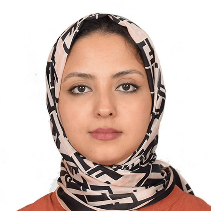 Houda Belaid in a close-up portrait wearing a patterned headscarf against a light background