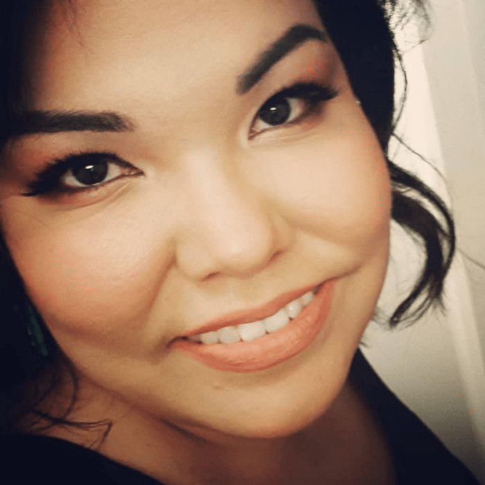 Lisa Rueckert smiling in a close-up portrait with dark hair and neutral background